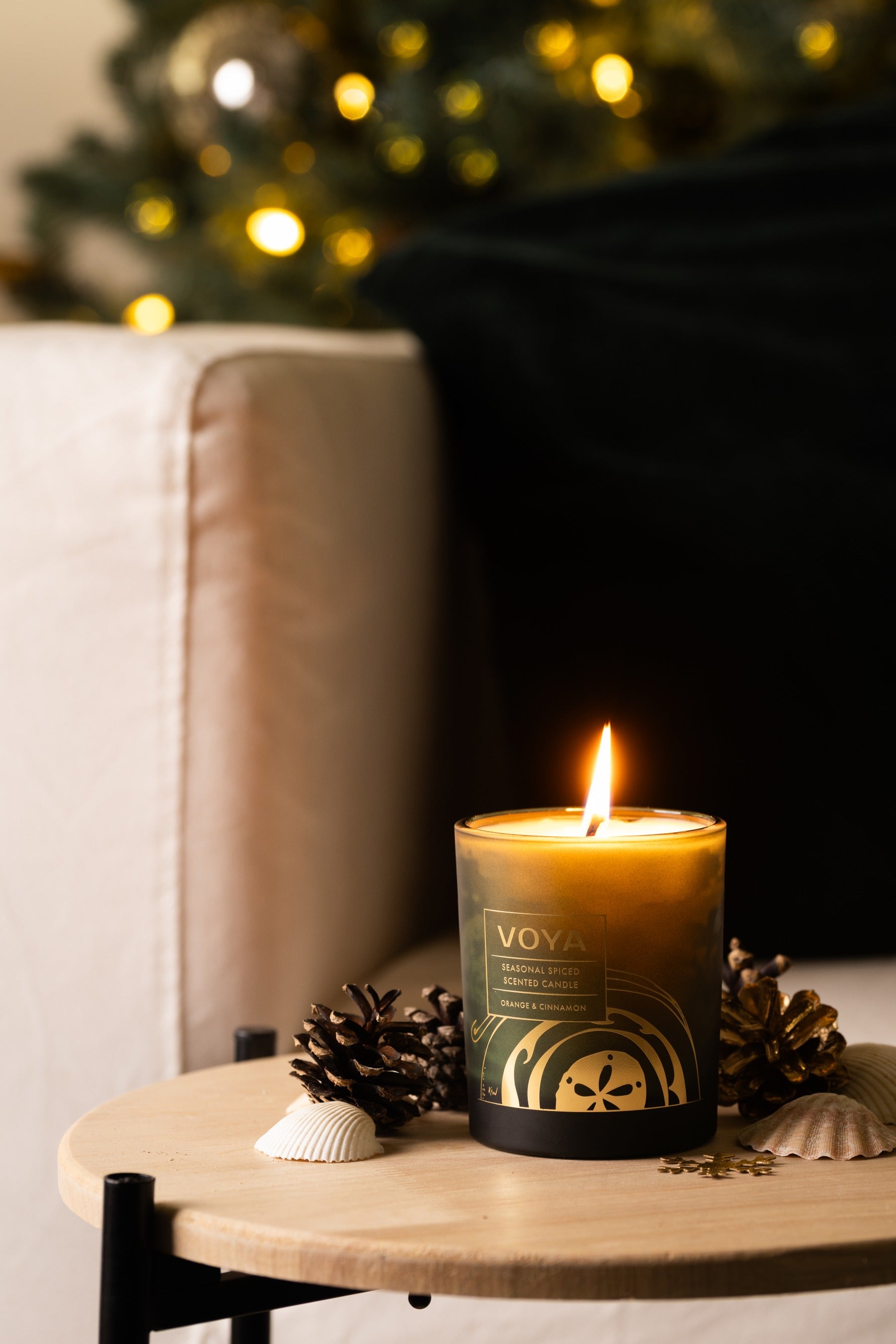 VOYA Seasonal Spiced Christmas Candle lite in front of Christmas tree