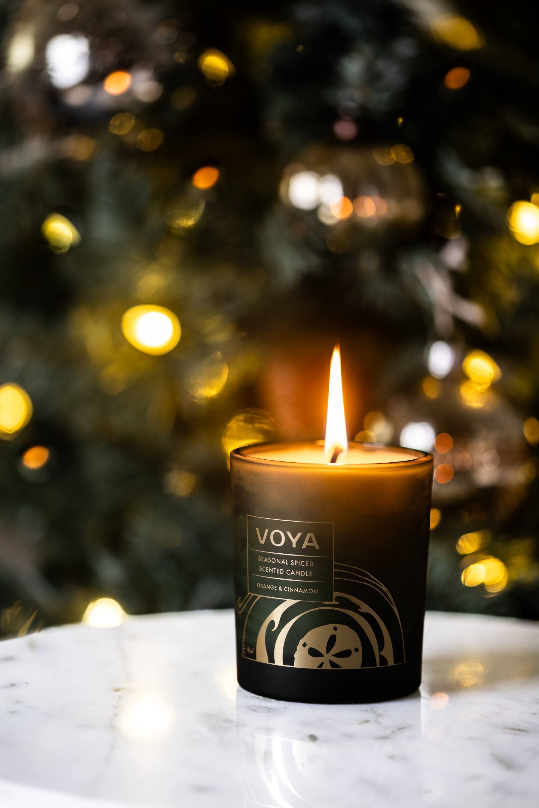 VOYA Seasonal Spiced Christmas Candle in front of a Christmas tree