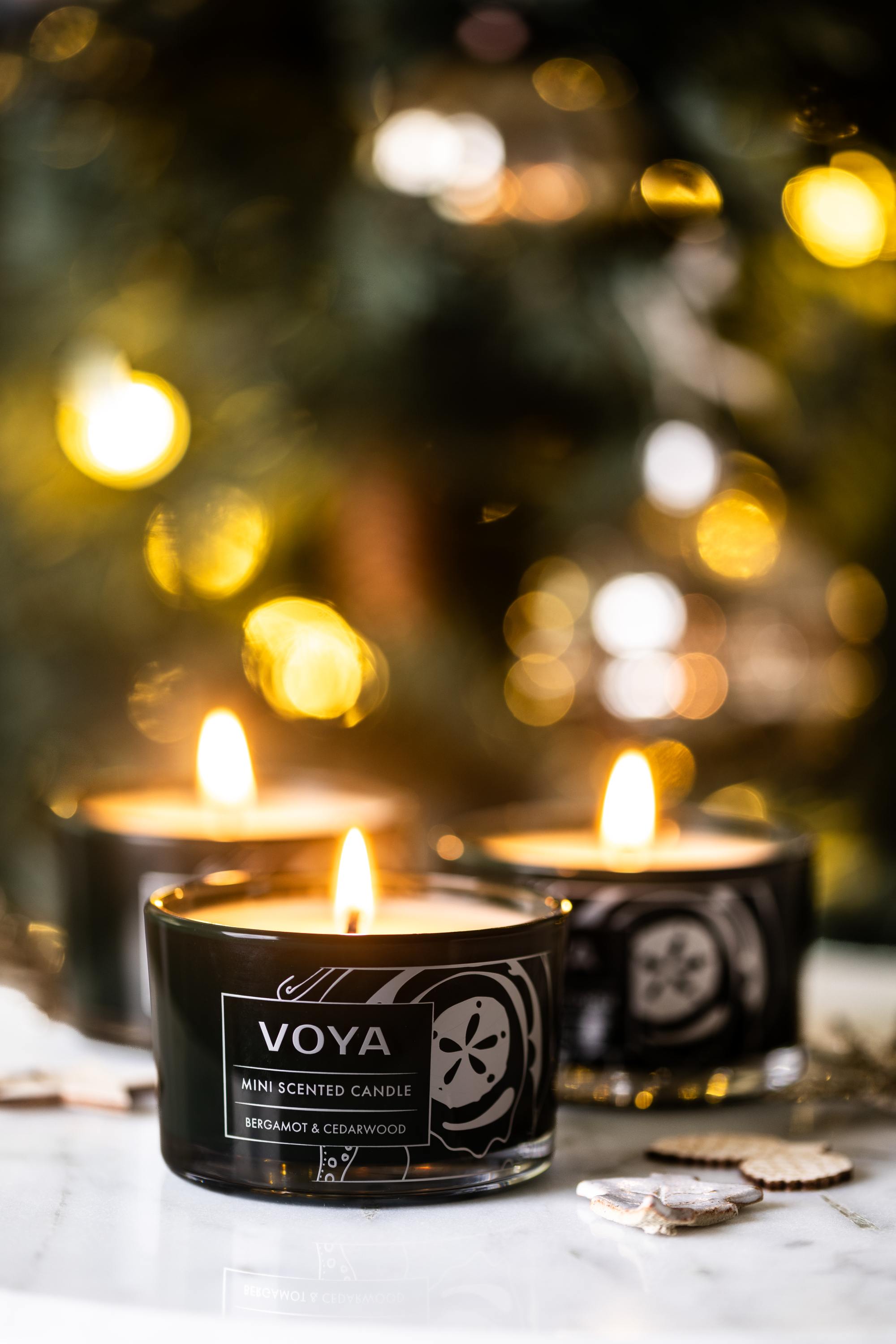 VOYA Blissful Sparks Mini Trio of Scented Candles in front of a Christmas Tree.